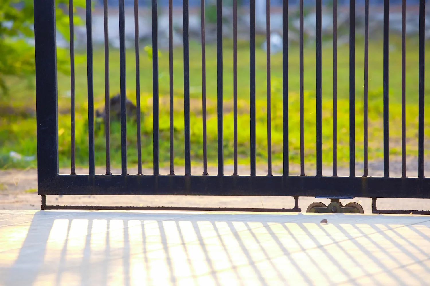 Black steel automatic sliding gate in front of a grassy paddock